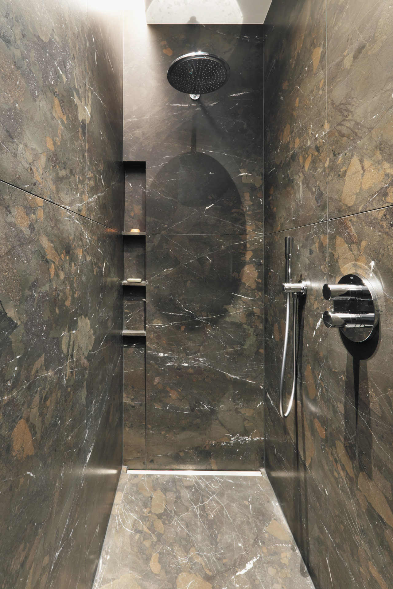 Bräunlicher Naturstein Breccia Imperiale mit feiner Maserung verbaut in der Dusche als Boden und Wandbelag