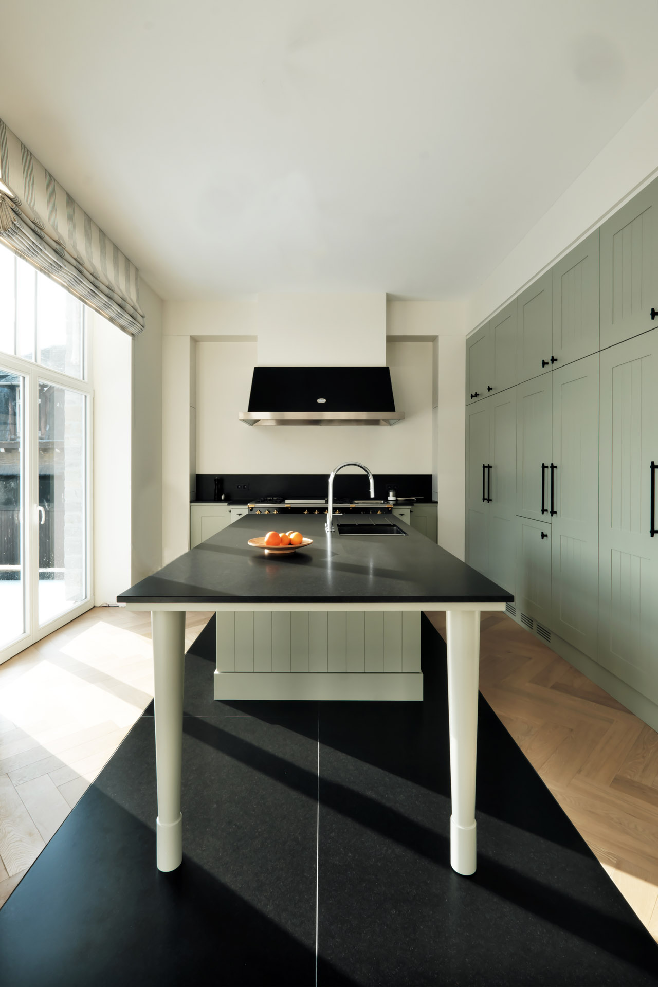 Ländliches Küchendesign mit olivfarbenem Holz und schwarzem Naturstein als Arbeitsplatte und passendem Küchenboden aus Nero Assoluto satiniert